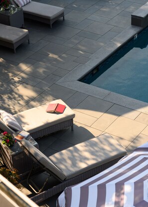 Una piscina al aire libre, sombrillas, sillones reclinables de piscina