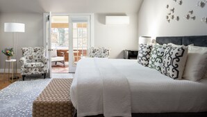 Un dormitorio con una cama grande, una mesita de noche, una lámpara, una silla y vistas al exterior.