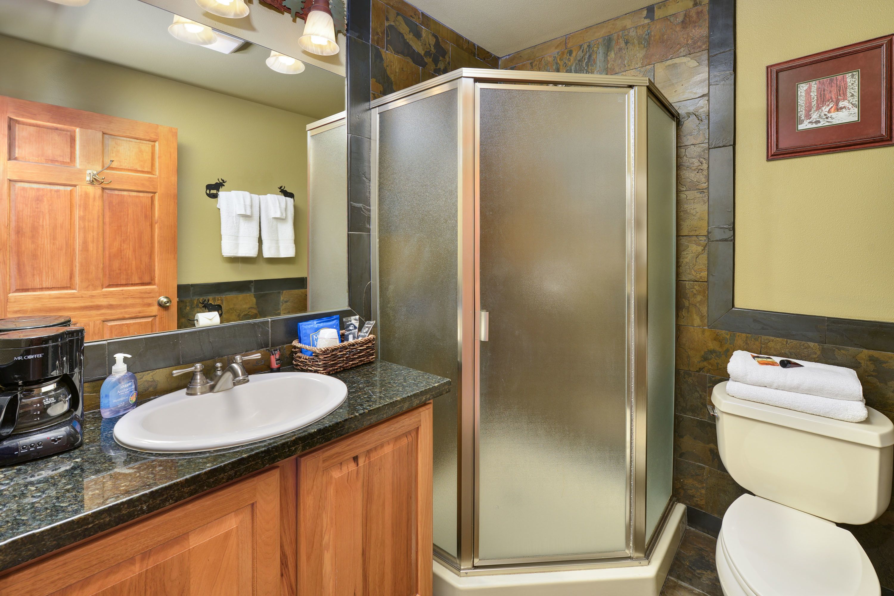 A bathroom with a shower enclosure, a sink, and a toilet.