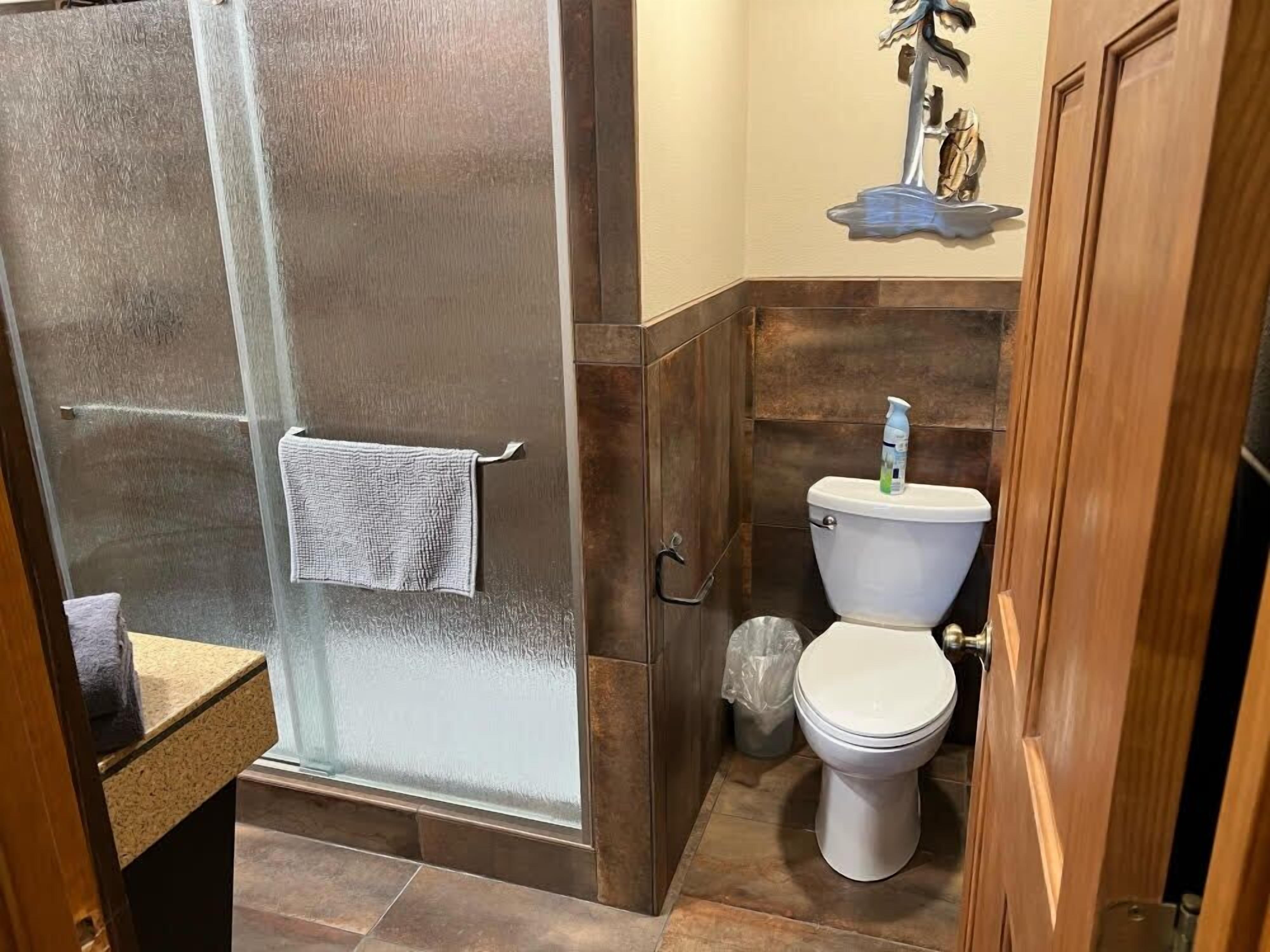 A bathroom with a glass shower enclosure, a toilet, and a sink.