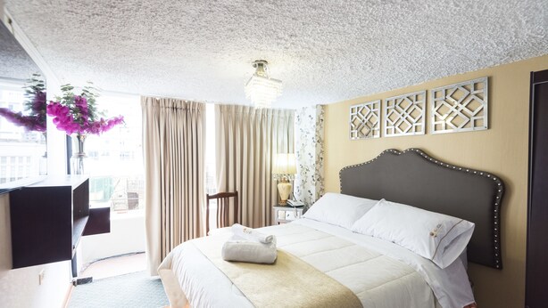 A hotel room with a large bed, a desk, and a view of the city.