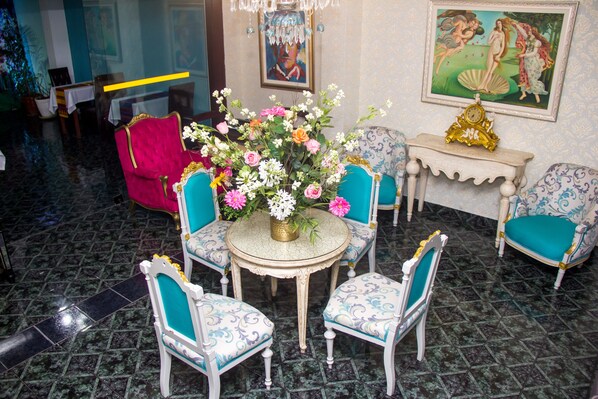 Ein Zimmer mit einem runden Tisch, der von vier Stühlen mit blauer Polsterung umgeben ist, einer Blumenvase und einer Uhr auf einem Beistelltisch.