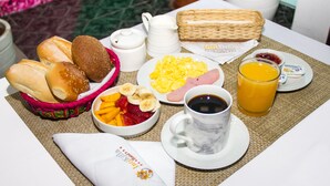 A breakfast table with bread, eggs, fruit, coffee, and juice.