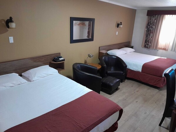 A hotel room with two beds, a desk, a chair, a nightstand, and a mirror. - Travellers Motel (Cranbrook)
