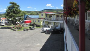 Un motel composé d’un bâtiment à deux étages, d’un parking où sont stationnés plusieurs véhicules, et dont l’arrière-plan est constitué par une chaîne de montagnes.