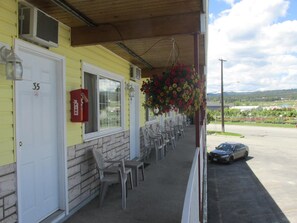 A yellow building with a fire extinguisher mounted on the wall, a fire hydrant, and a row of chairs outside. - Travellers Motel (Cranbrook)