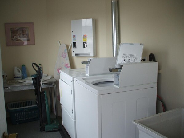 A laundry area with a washing machine, dryer, and a utility cabinet. - Travellers Motel (Cranbrook)