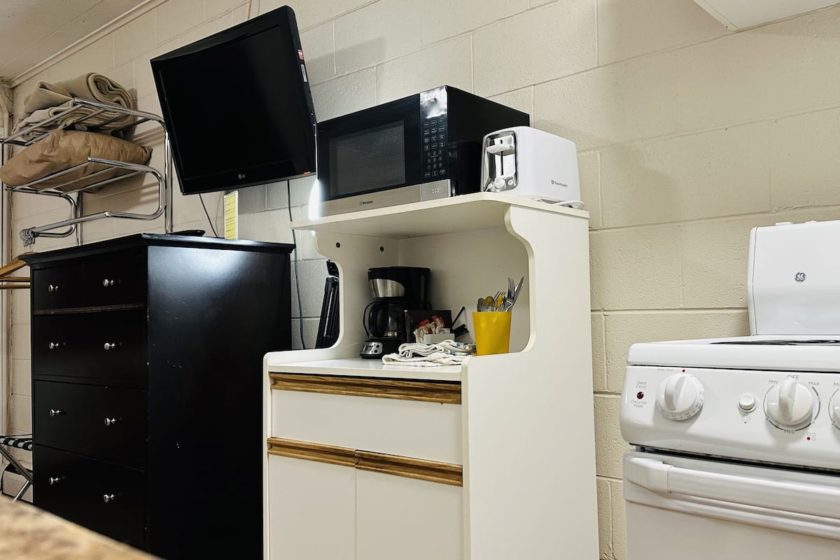 Cozinha compacta equipada com micro-ondas, torradeira, cafeteira e fogão.