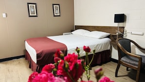 Une chambre d’hôtel équipée d’un lit, d’une chaise, d’une table de chevet et d’une prise de courant fixée au mur.