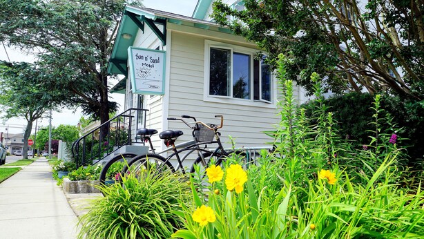 A motel with a sign reading "Sun n' Sand Motel" and a bicycle parked in front.