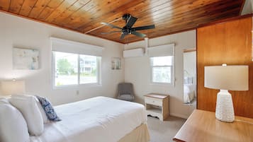 Un dormitorio con cama, escritorio, silla, ventilador de techo y ventana.