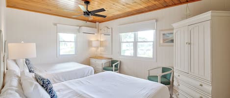 Ein Schlafzimmer mit zwei Betten, einem Deckenventilator, einem Schminktisch und einem Fenster.