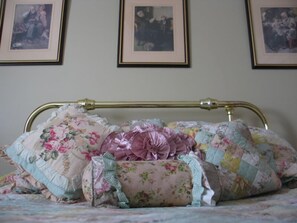 Ein Bett mit blumigem Bettzeug und einem Messing-Kopfteil.