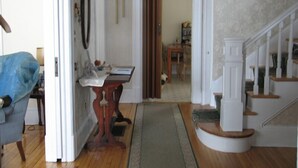 A hallway with a wooden floor, a white staircase, and a door leading to another room. - Downtown Bed And Breakfast (Moncton)