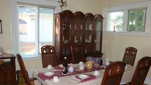 A dining room with a wooden table set for four, surrounded by chairs, and a china cabinet in the background. - Downtown Bed And Breakfast (Moncton)