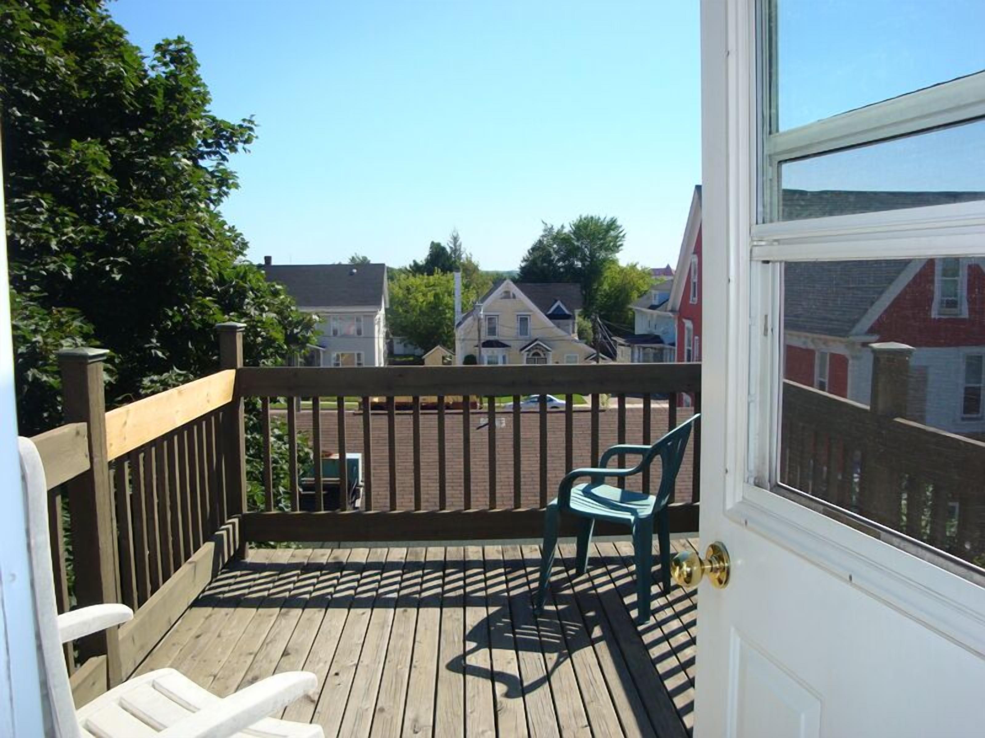A wooden deck with two chairs and a view of houses in the background.