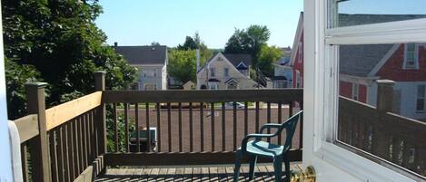 A wooden deck with two chairs and a view of houses in the background.