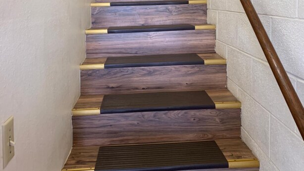 A staircase with alternating wooden steps and a wooden handrail.