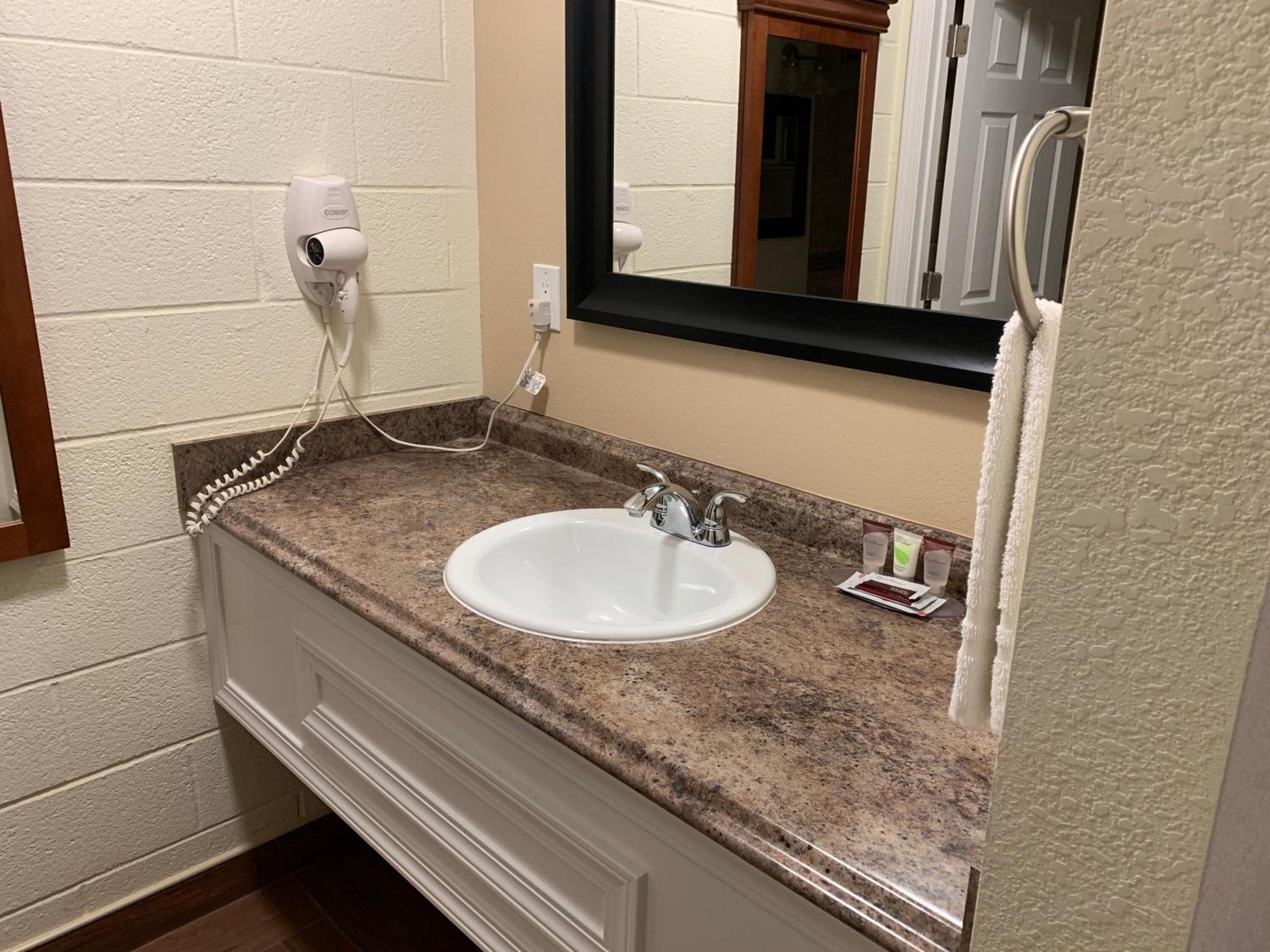 A bathroom with a white sink, granite countertop, and a mirror above the sink.