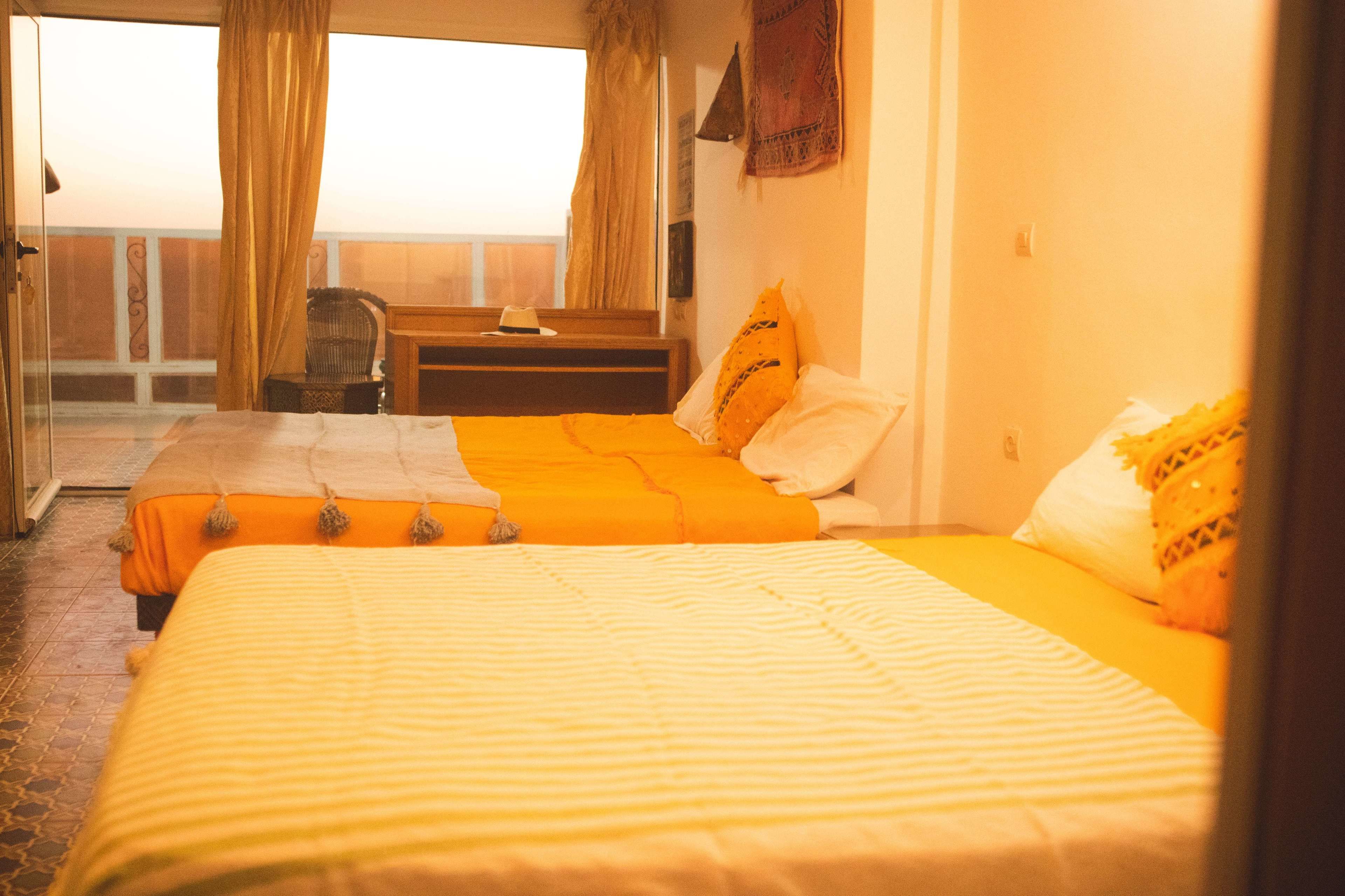 A hotel room with a bed, a chair, a small table, and a view of the outside.