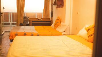 A hotel room with a bed, a chair, a small table, and a view of the outside.