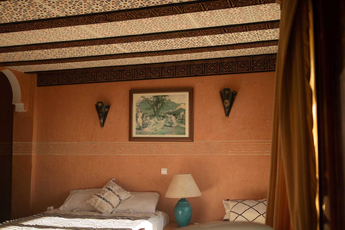 Ein Schlafzimmer mit einem Bett, einem Nachttisch, einer Lampe und einem gerahmten Bild an der Wand.