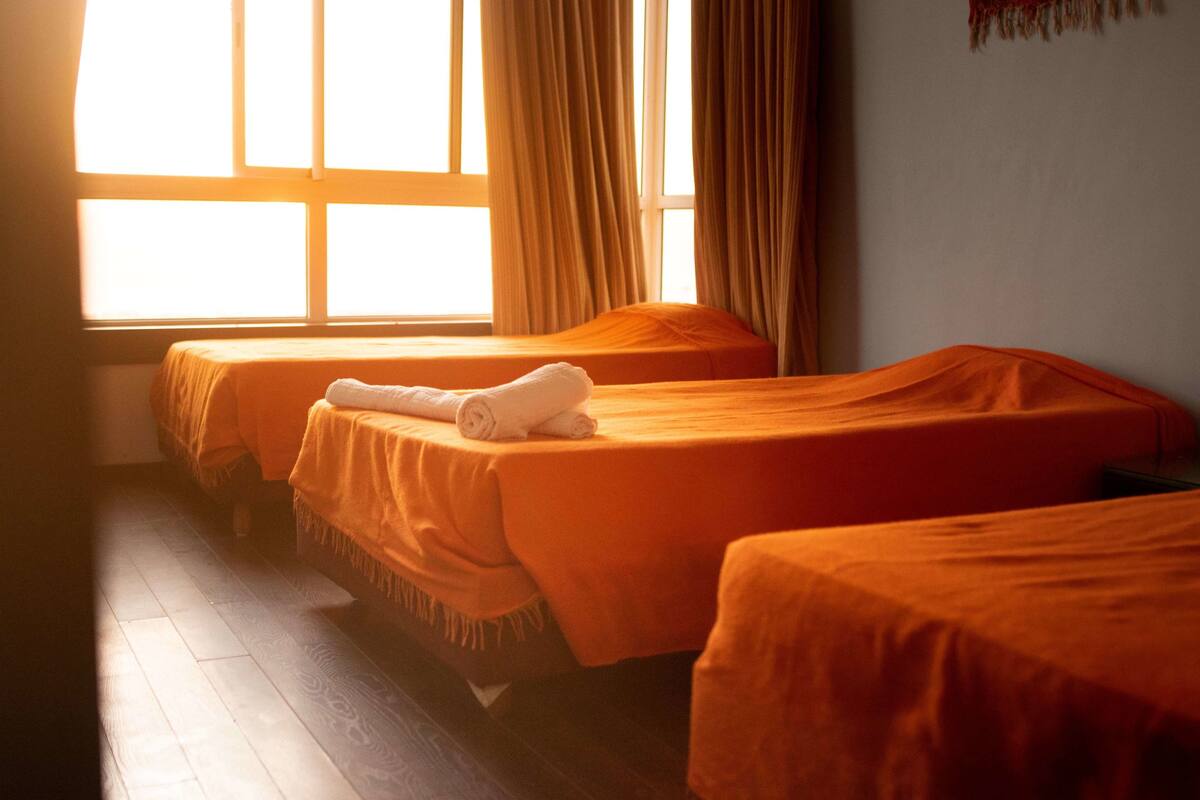 Ein Zimmer mit zwei Betten, einem Vorhangfenster und Holzboden.