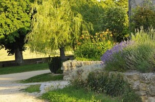 Un muro de piedra con diversas plantas y un sendero que lleva a un edificio.
