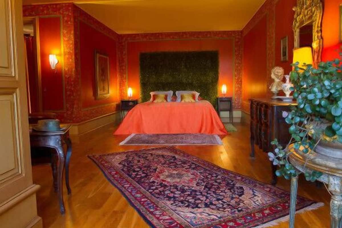 Una habitación con una cama grande, un tapete decorativo y un espejo con una estatua.