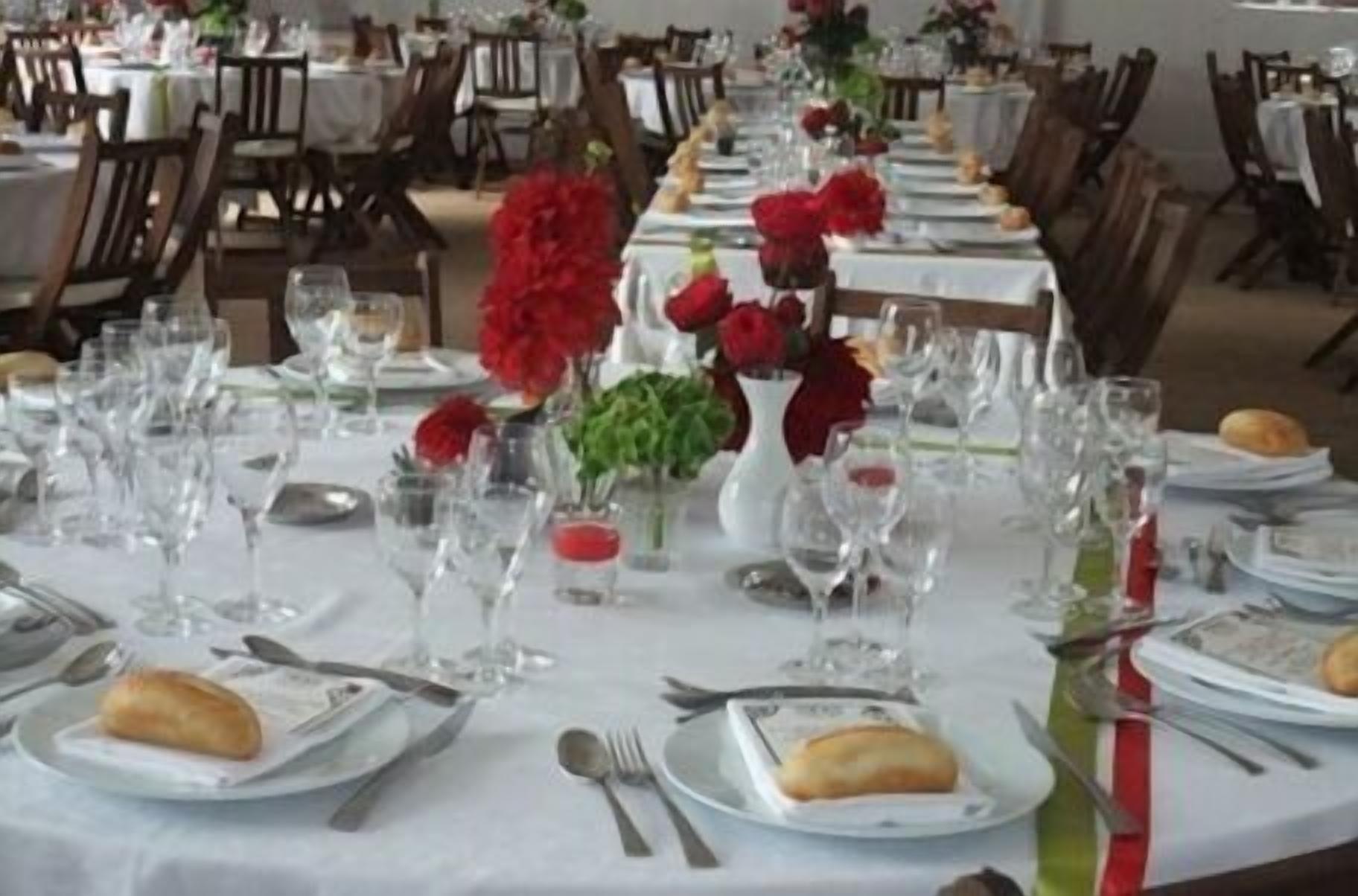 Un comedor con mesas dispuestas para una comida, con platos, cubiertos y vasos.