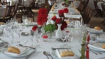 Un comedor con mesas dispuestas para una comida, con platos, cubiertos y vasos.