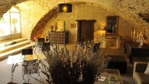 Un interior rústico con techo de piedra, chimenea y zona de estar con una mesa de centro y sillas.