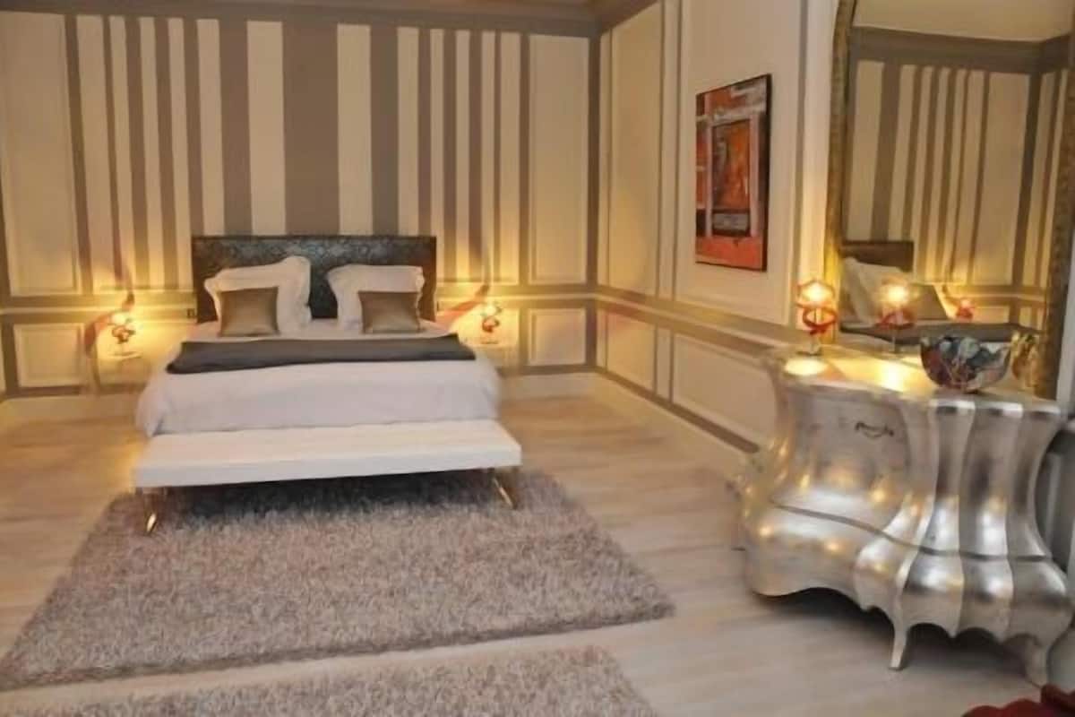 Un dormitorio con cama, mesitas de noche, una alfombra y un espejo.