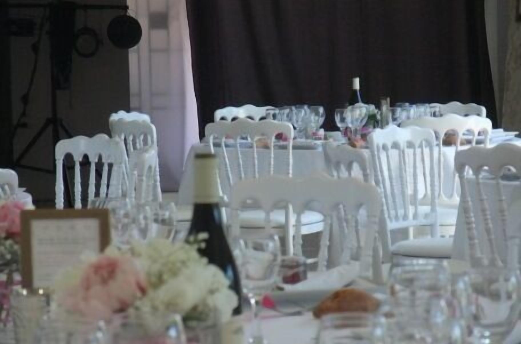 A table set for a formal event with white chairs and clear glassware.