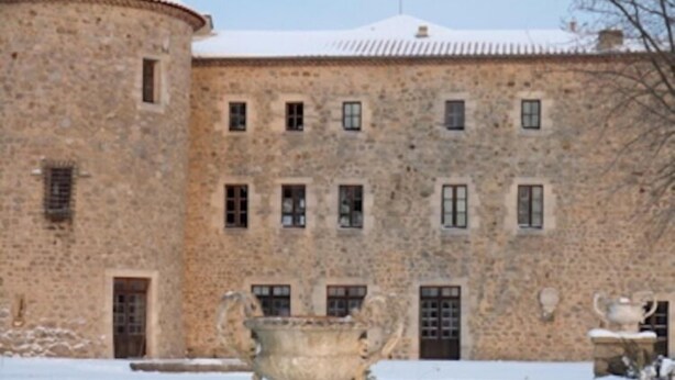 Un edificio de piedra con numerosas ventanas y un patio cubierto de nieve.