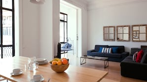 A living room with a wooden table, a bowl of fruit, and a blue sofa. - My Address in Barcelona (Barcelona)