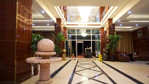 A lobby with a marble fountain, a reception desk, and a seating area with leather chairs.
