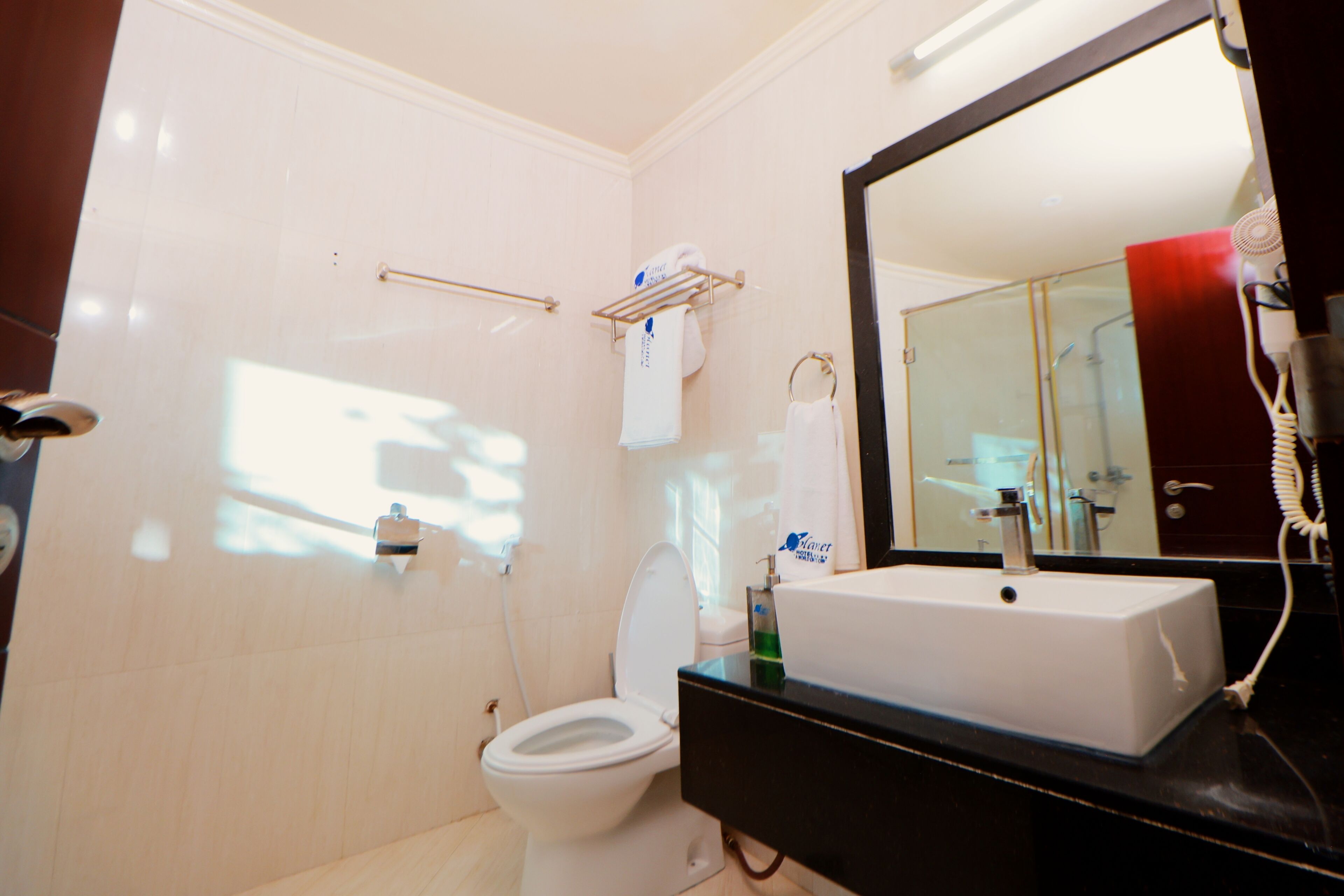 A bathroom with a white toilet, a sink, a mirror, and a towel rack.