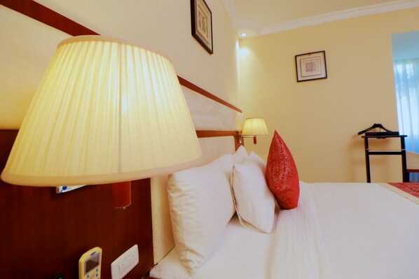 A hotel room with a bed, a large wall-mounted lamp, a bedside table, a chair, and a framed picture on the wall. - Planet Hotel (Mek'ele)