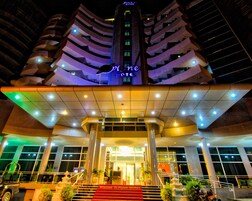 Un hotel con un diseño espiral distintivo, una entrada destacada con alfombra roja y un letrero que dice “Planet Hotel”.