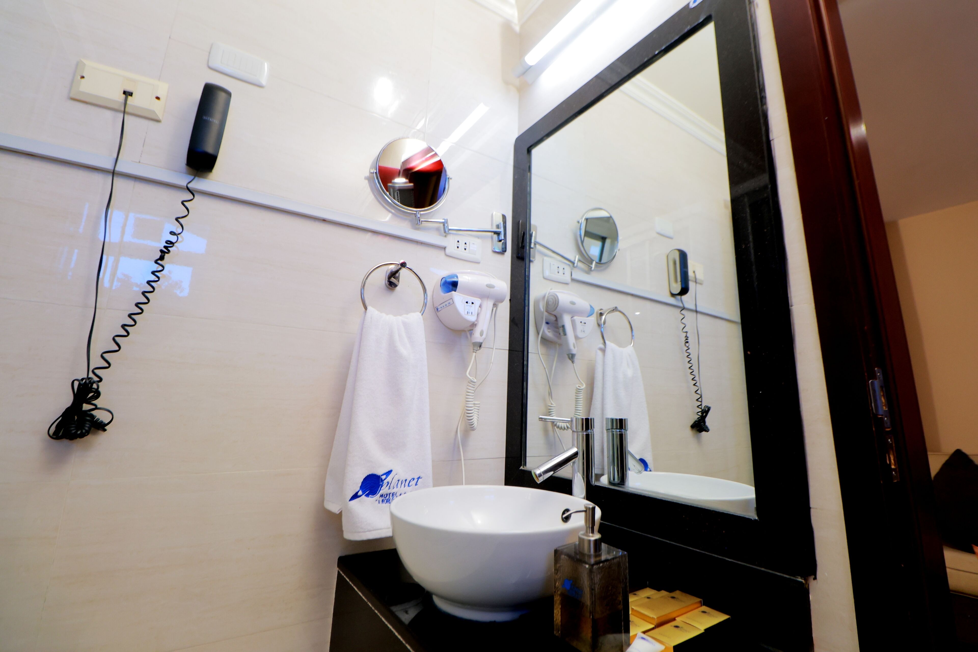 A bathroom with a white sink, a mirror, a hairdryer, and a towel ring.