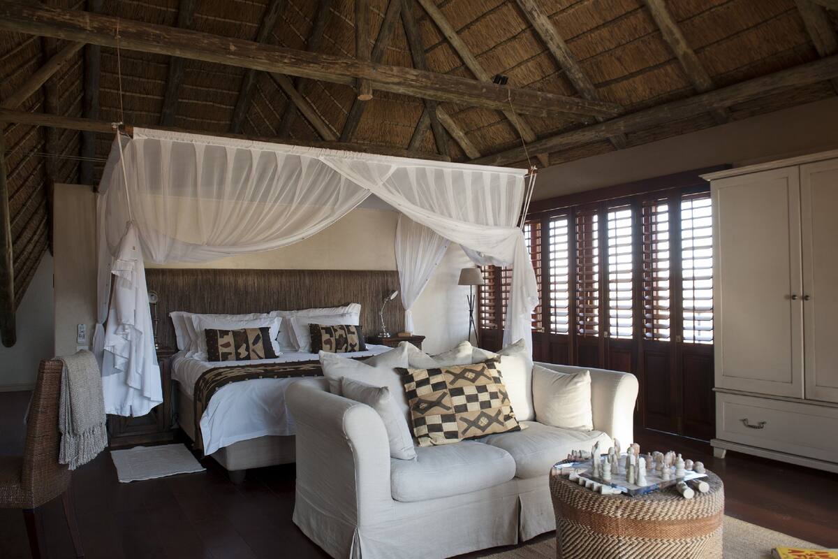 A bedroom with a four-poster bed, a sofa, and a nightstand.