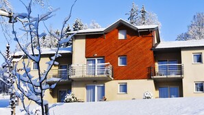 A multi-story building with a wooden facade and balconies. - Résidence Le Herbau (Gerardmer)