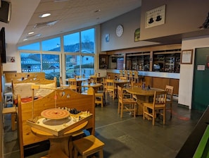 Un restaurante acogedor con mobiliario de madera, un tablero de ajedrez y una zona de bar.