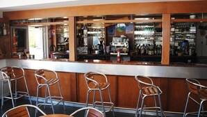 A bar area with a counter, stools, and shelves stocked with bottles. - Résidence Le Herbau (Gerardmer)