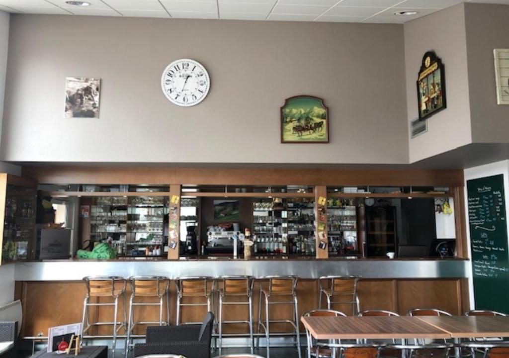 A bar area with a clock, seating, and a menu board.
