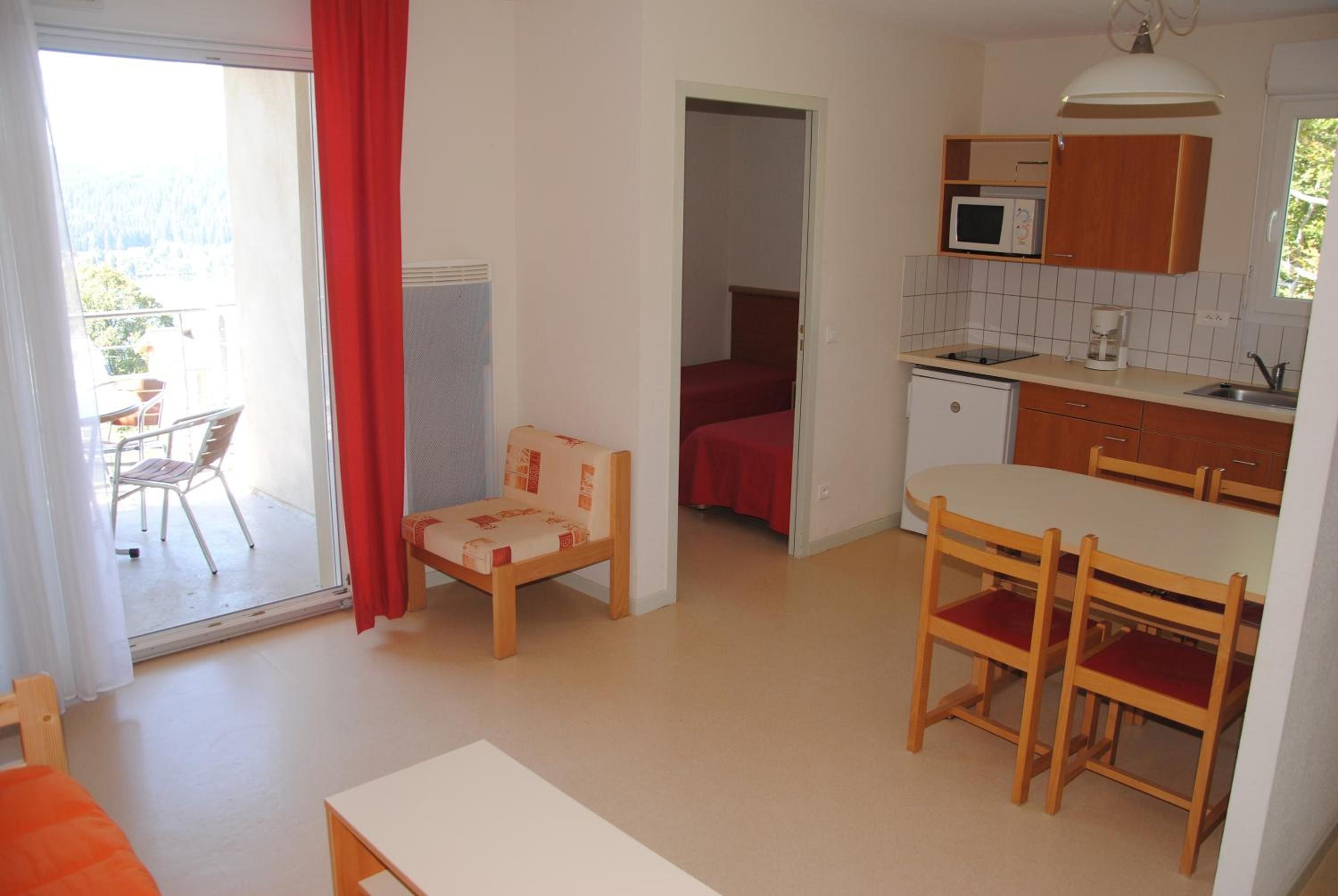 A compact living space with a kitchenette, a dining area, and a small bedroom.