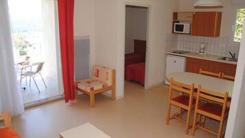 A compact living space with a kitchenette, a dining area, and a small bedroom.