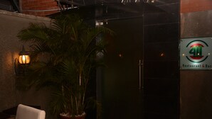 A potted plant, a chair, and a wall-mounted sign for a restaurant and bar. - Fryburg Suites (Lagos)