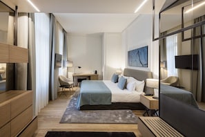 Relax in a serene space with a large bed, bedside table, and desk, surrounded by a neutral color palette and natural light-inspired decor.